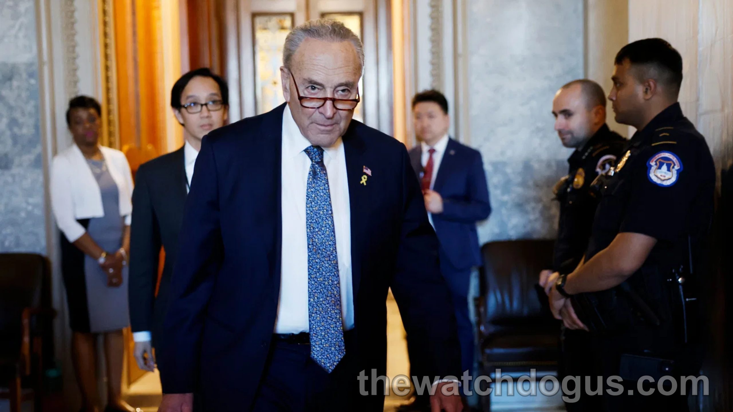 Senior politician in blue suit and blue tie walking through corridor with staff during Schumer Obamacare shutdown negotiations