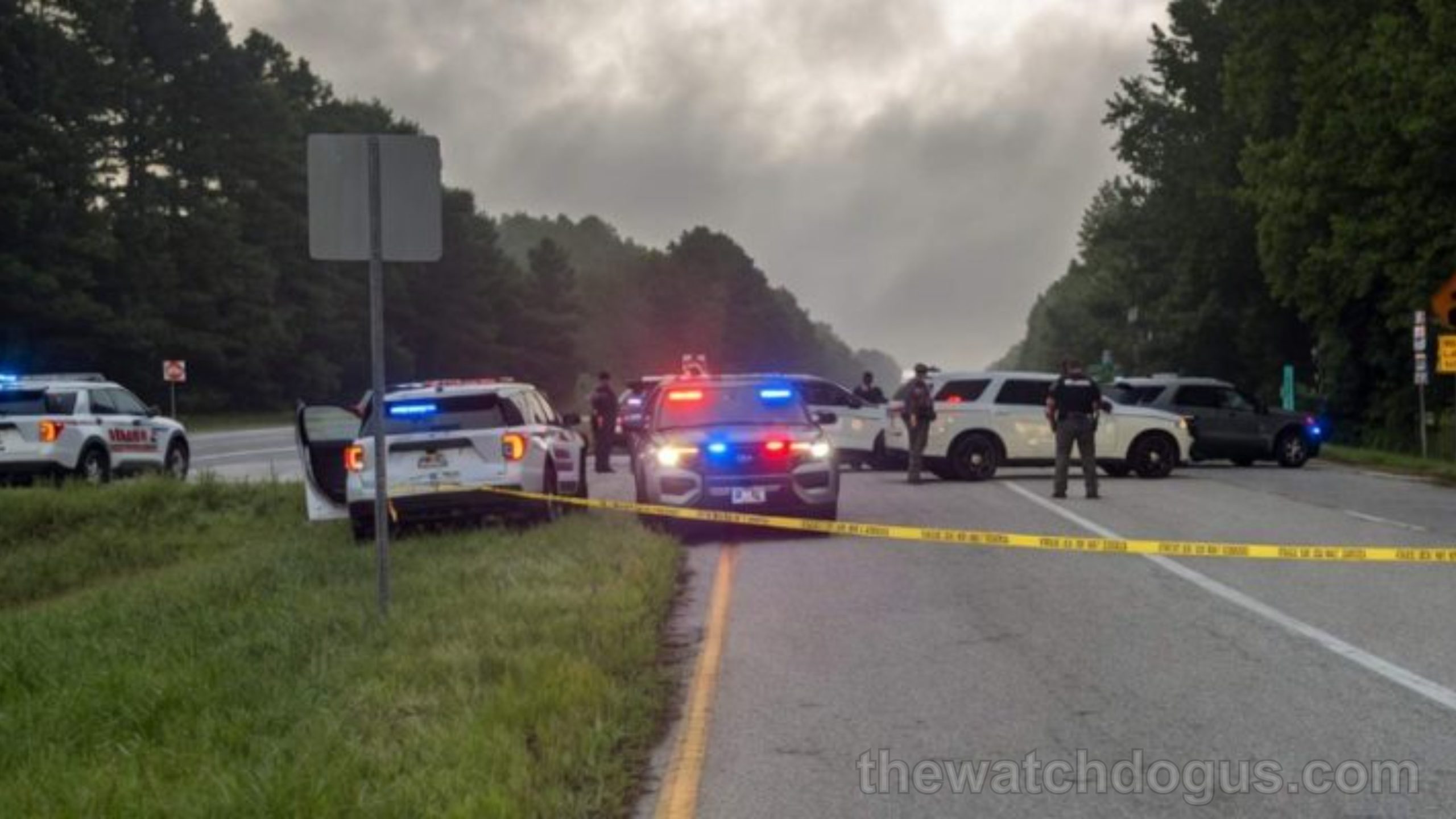Police vehicles and officers establishing a police warning zone on a highway with yellow caution tape