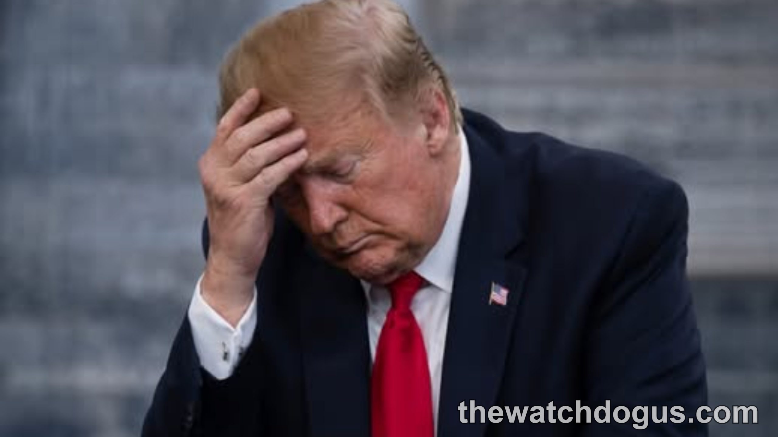 Man in dark suit and red tie holding head in distressed gesture