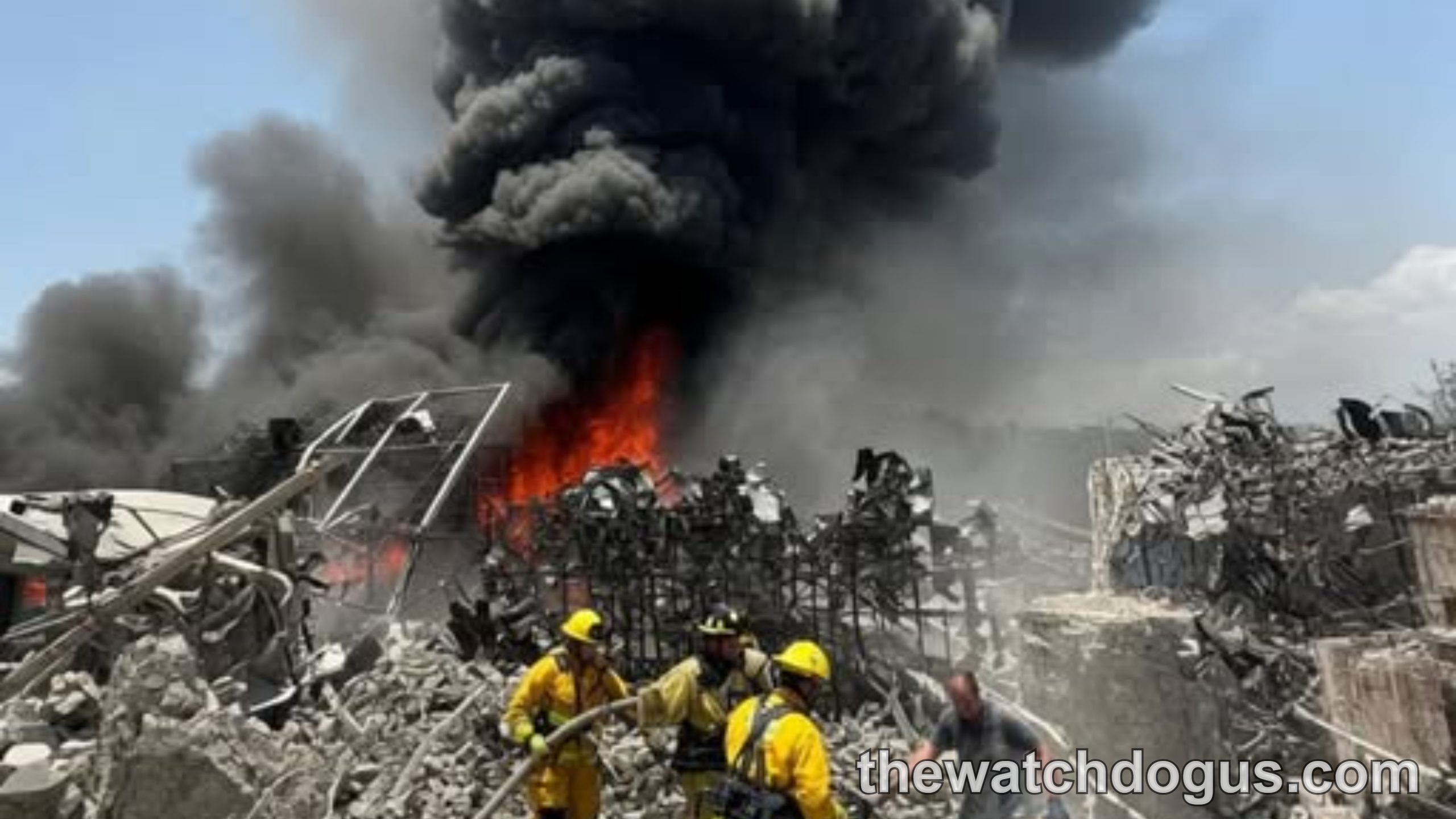 Firefighters in yellow gear battle massive industrial fire in Greece with thick black smoke and flames engulfing destroyed structures