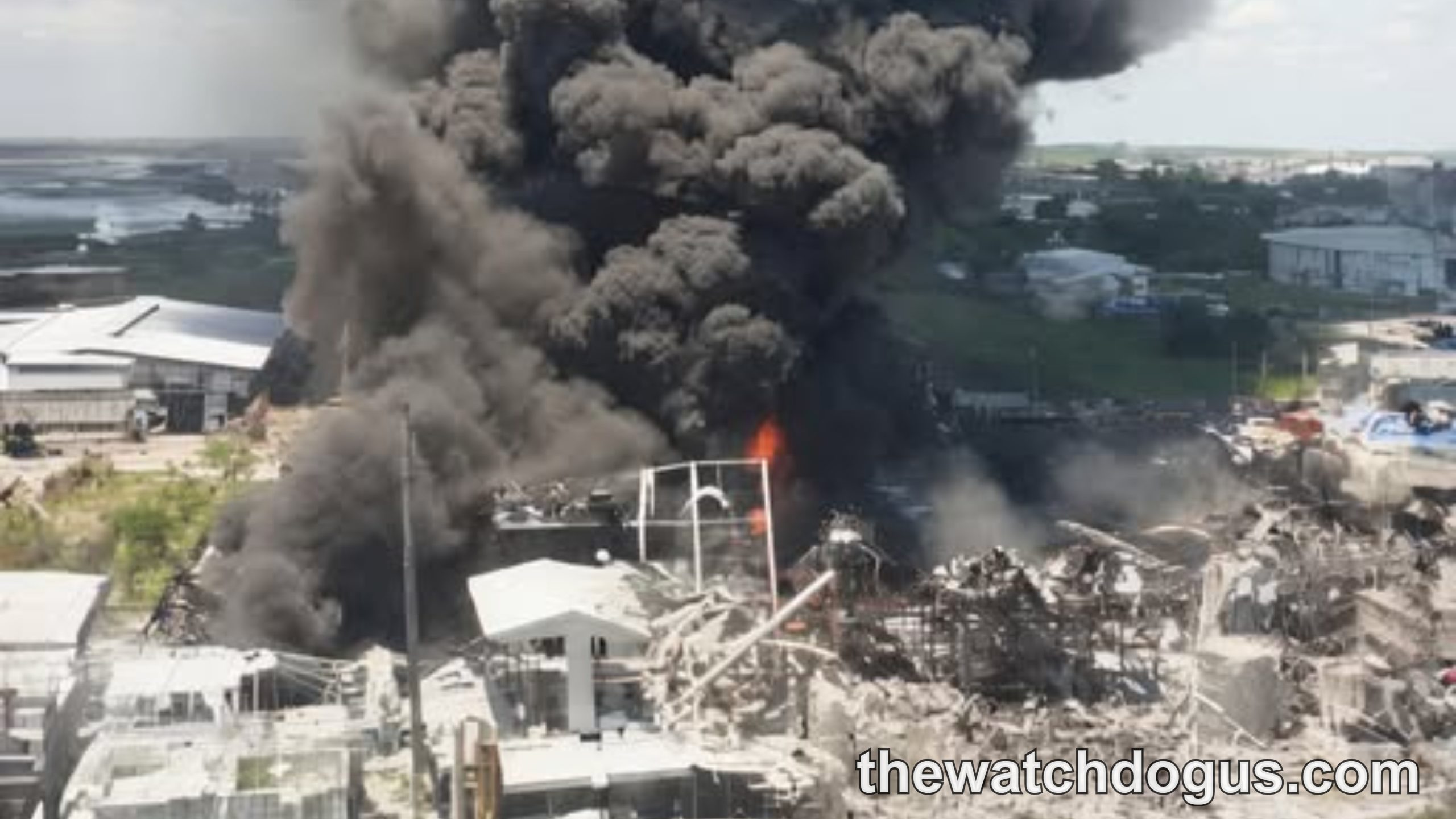 Large plume of dark smoke rising from Greek factory fire with industrial buildings and surrounding landscape visible