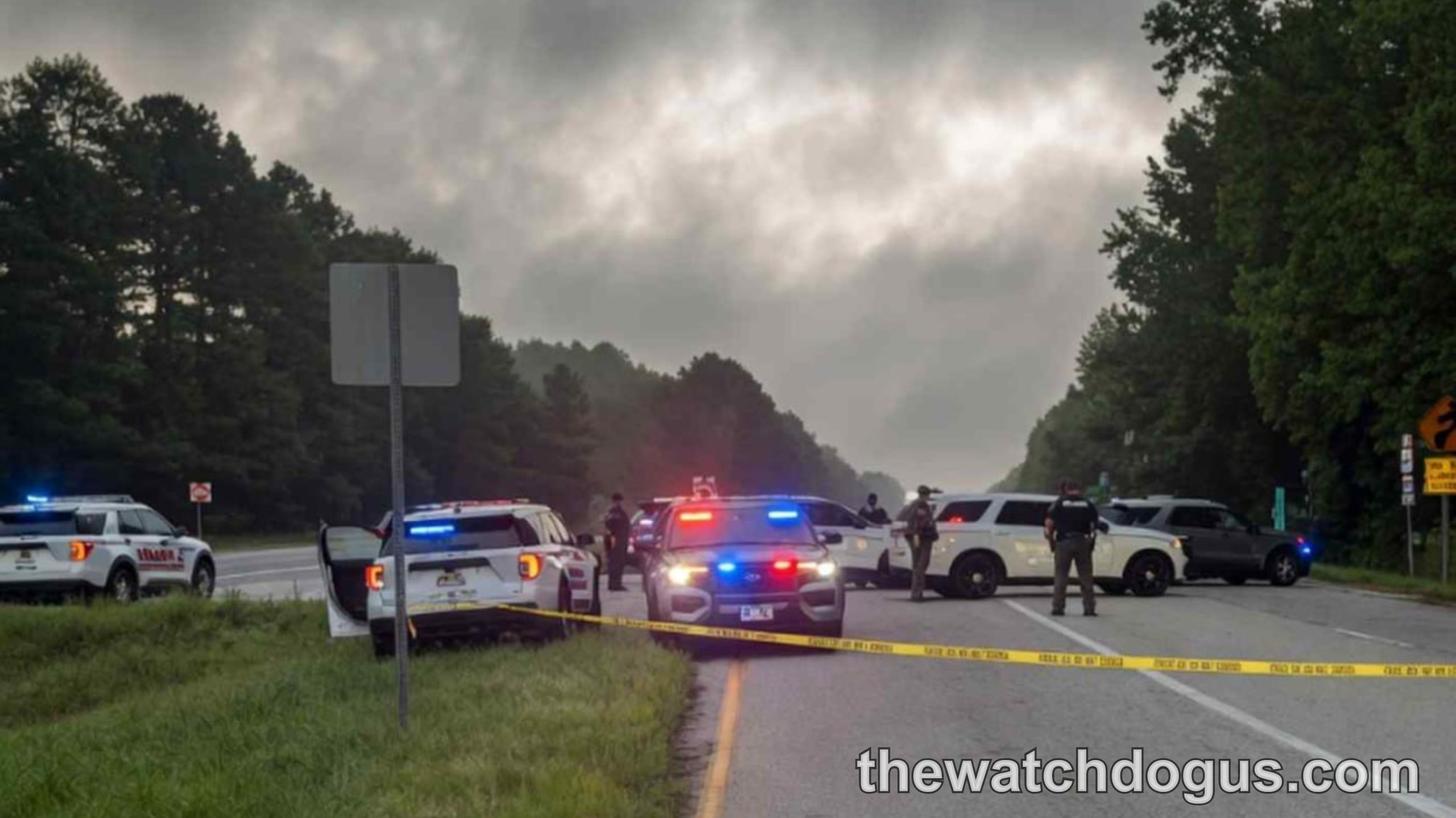 Multiple police vehicles with emergency lights on highway with yellow crime scene tape during police safety advisory incident