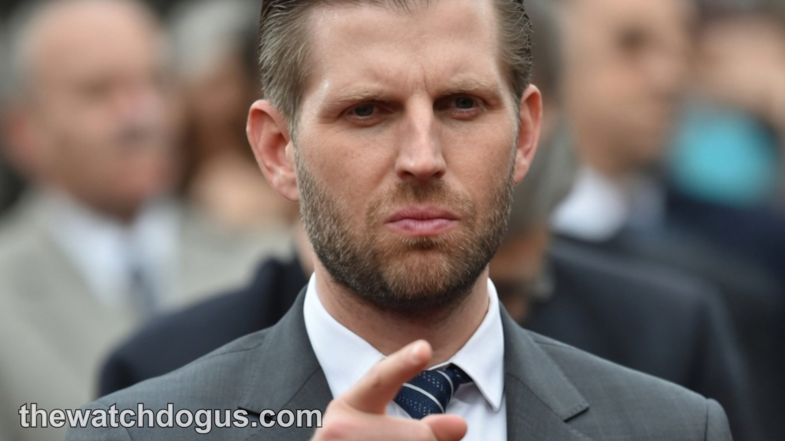 Eric Trump confirmed at public event wearing gray suit and navy striped tie, pointing at camera