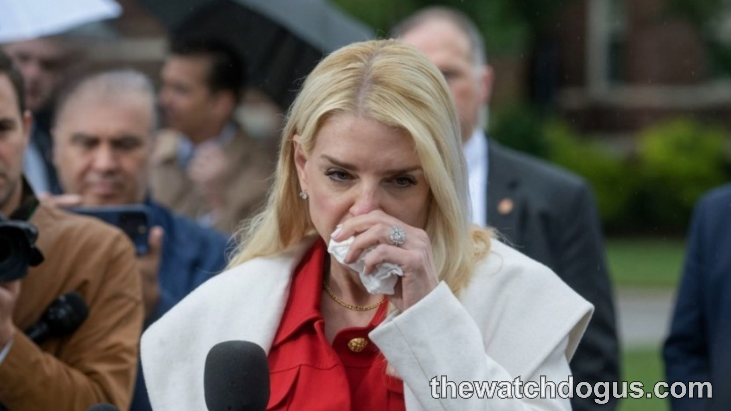 Pam Bondi Attorney General speaking at outdoor event wearing red jacket and white coat