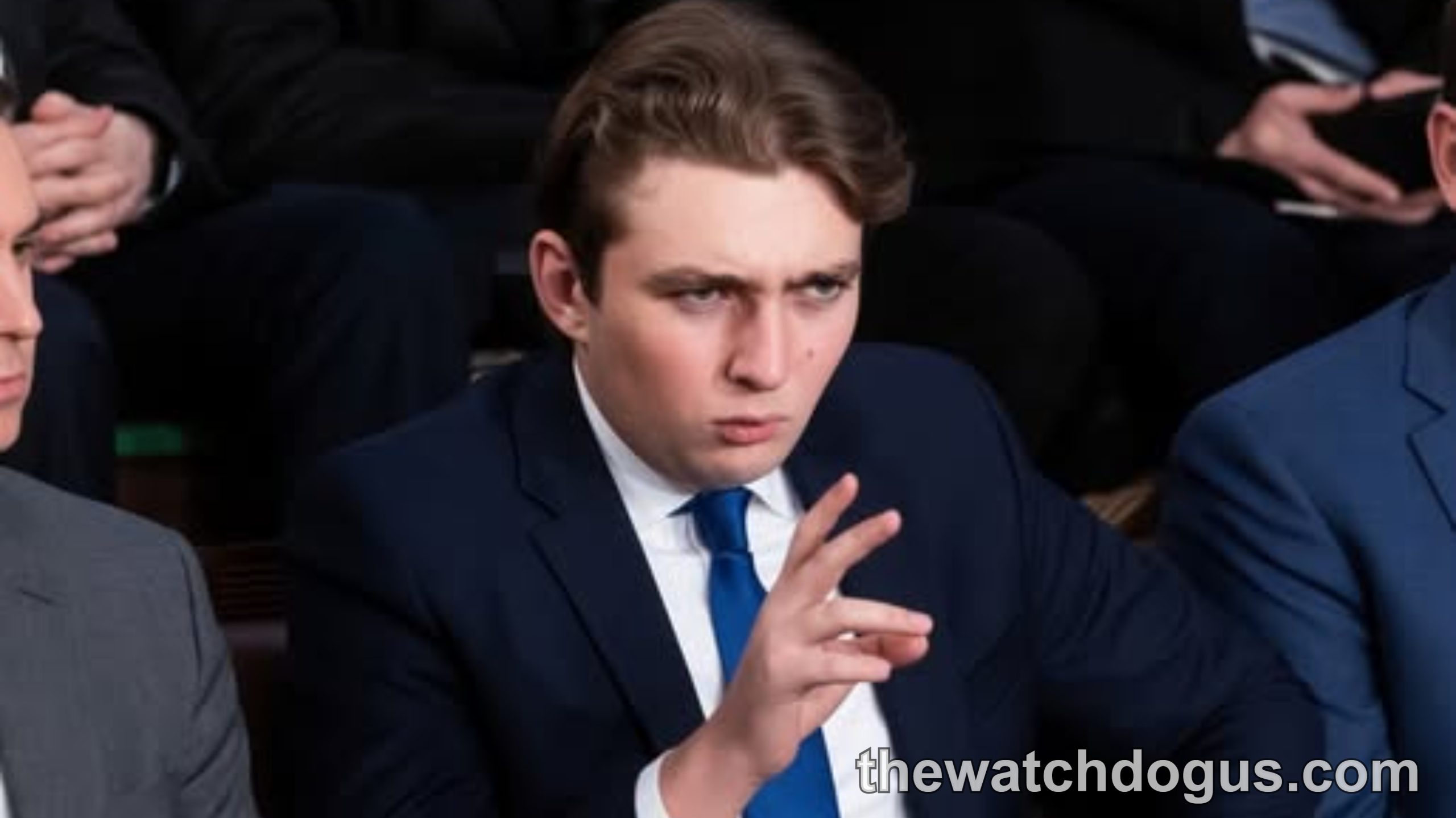 Young man in navy suit at formal event amid discussion of political families and military service debate