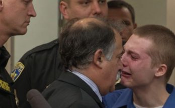 Young defendant in blue shirt during juvenile sentencing prison hearing with law enforcement officers present in courtroom