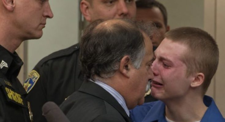 Young defendant in blue shirt during juvenile sentencing prison hearing with law enforcement officers present in courtroom