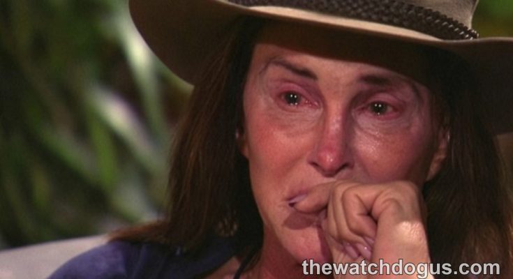 Person wearing brown cowboy hat with long dark hair, hand to face in contemplative expression
