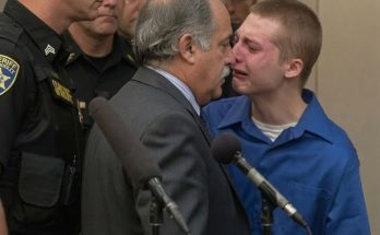 Young man in blue shirt with gray-haired man in suit during juvenile sentencing hearing with sheriff officers present
