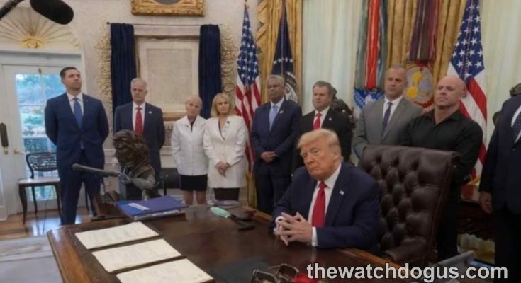 Judge resigns Trump administration official seated at Oval Office desk with staff members standing in background