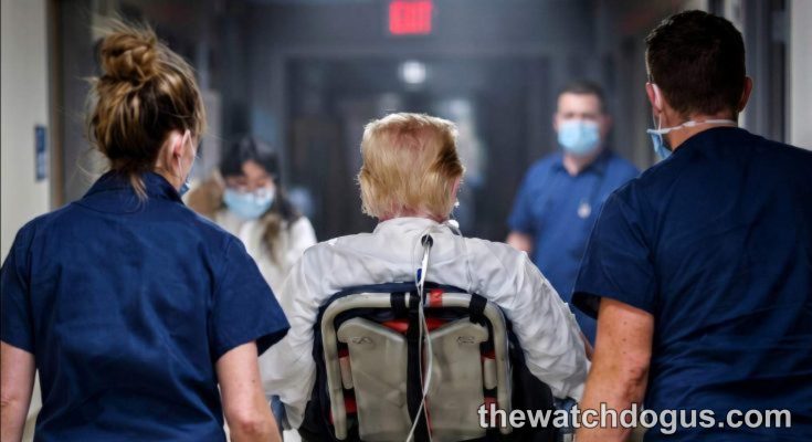 Healthcare workers escort elderly patient in wheelchair during Trump cognitive assessment evaluation at medical facility