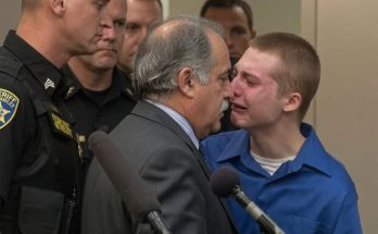 Young defendant in blue shirt speaks with attorney during juvenile sentencing hearing in courtroom with law enforcement present