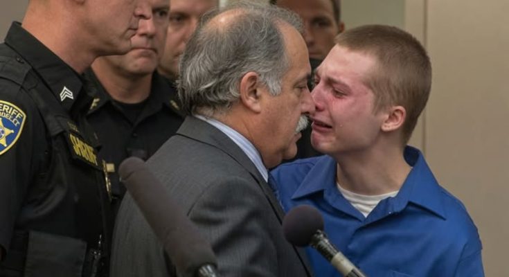 Young defendant in blue shirt speaks with attorney during juvenile sentencing hearing in courtroom with law enforcement present