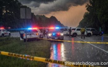 Police vehicles with flashing lights establishing a security perimeter on rainy highway during emergency operation