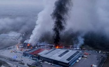 Aerial view of Greece factory fire with massive smoke plume rising from industrial building with solar panels